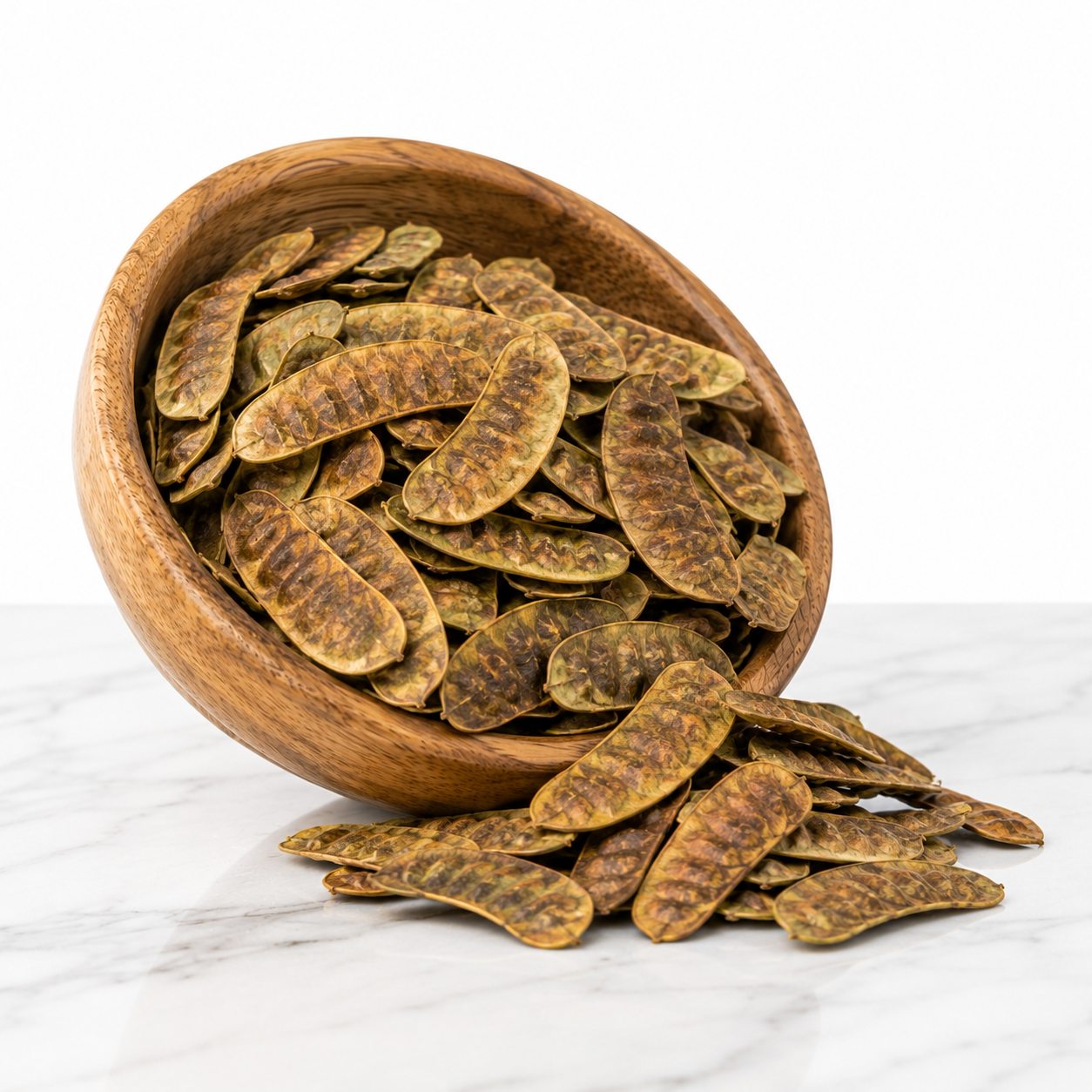 Dried senna pods spilling from a wooden bowl